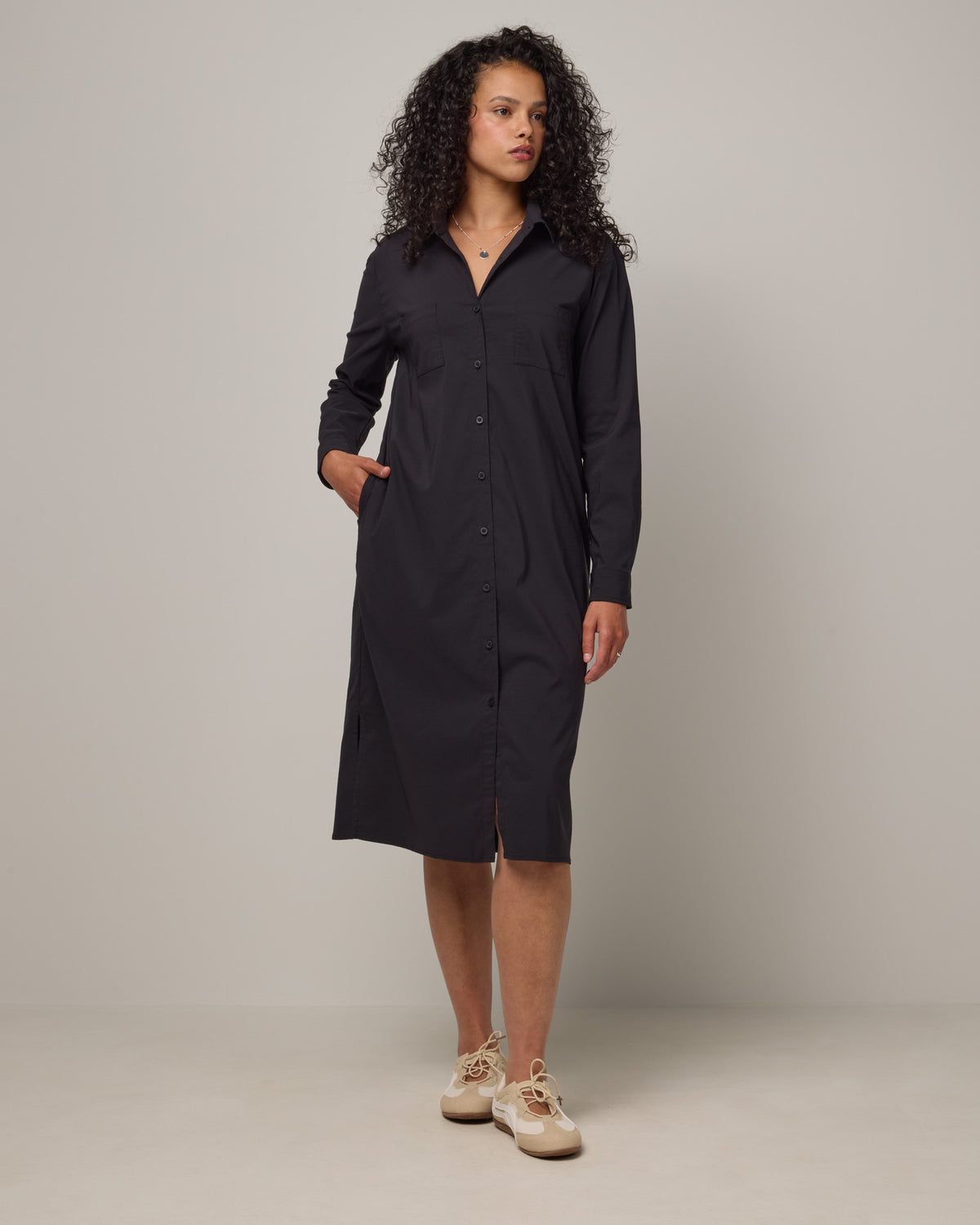 Model wearing Victoria Shirt Dress in Black. Victoria Shirt Dress is a merino wool long sleeve, midi length, button-front dress with pockets and removable belt available in sizes XS-XXL.