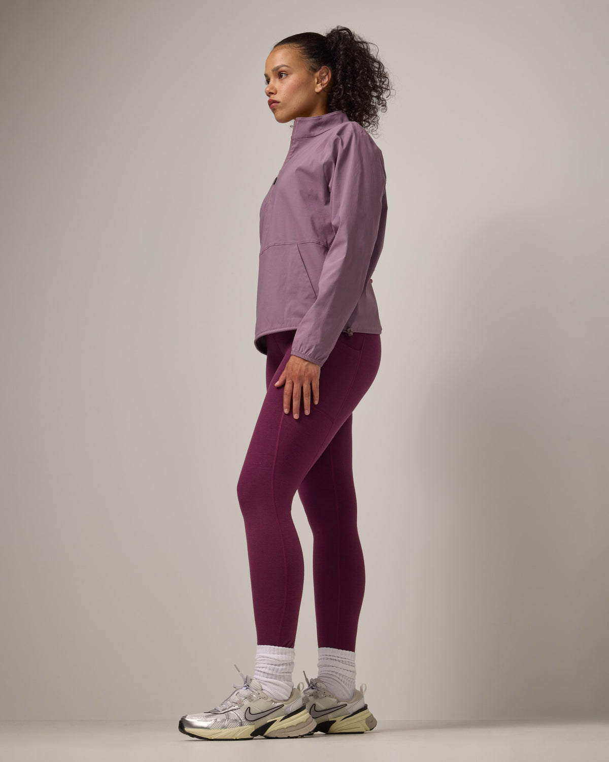 Model wearing Venus Quarter Zip in Lavender. Venus Quarter Zip is a merino wool lightweight long sleeve pullover with a front pocket available in sizes XS-XXL.