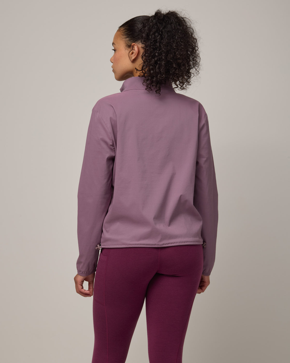 Model wearing Venus Quarter Zip in Lavender. Venus Quarter Zip is a merino wool lightweight long sleeve pullover with a front pocket available in sizes XS-XXL.