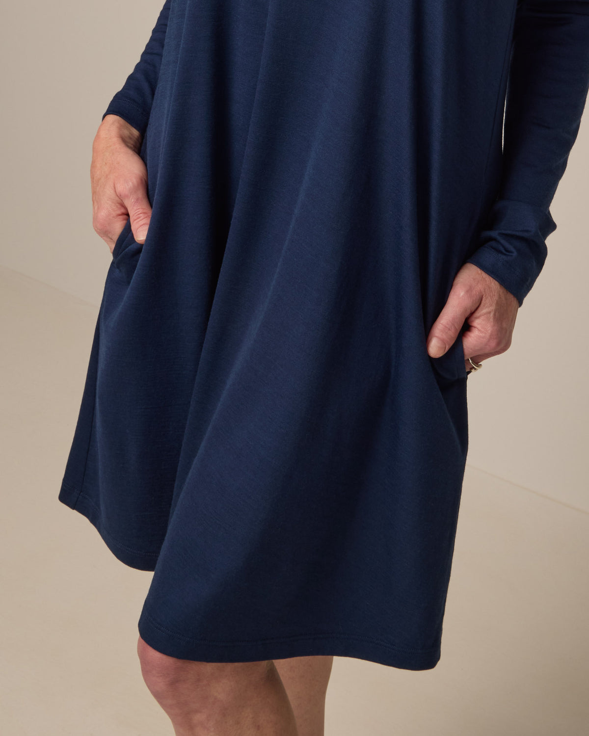 Model wearing Rowena Swing Dress in Marine Blue, a deep royal blue color. Rowena Swing Dress is a merino wool long sleeve, boatneck, knee length swing dress with pockets available in sizes XS-3X Regular, XS-3X Long.
