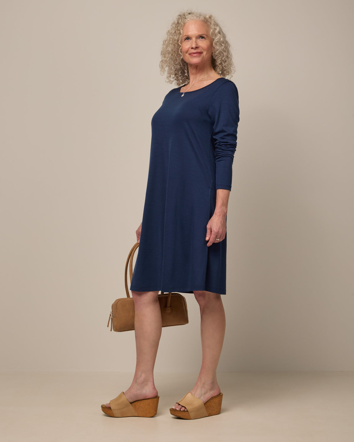 Model wearing Rowena Swing Dress in Marine Blue, a deep royal blue color. Rowena Swing Dress is a merino wool long sleeve, boatneck, knee length swing dress with pockets available in sizes XS-3X Regular, XS-3X Long.