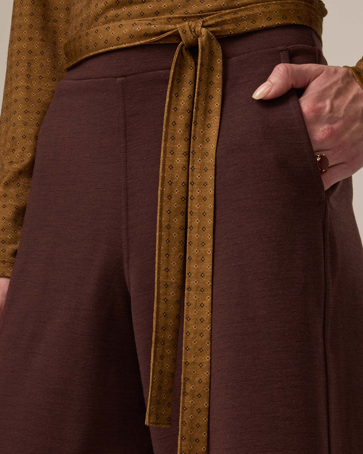 Model wearing Lane Wide Leg Ponte Pant in Espresso, a warm brown color. Lane Wide Leg Ponte Pant is a merino wool pant with pockets available in sizes XS-3X Regular, XS-XXL Long.