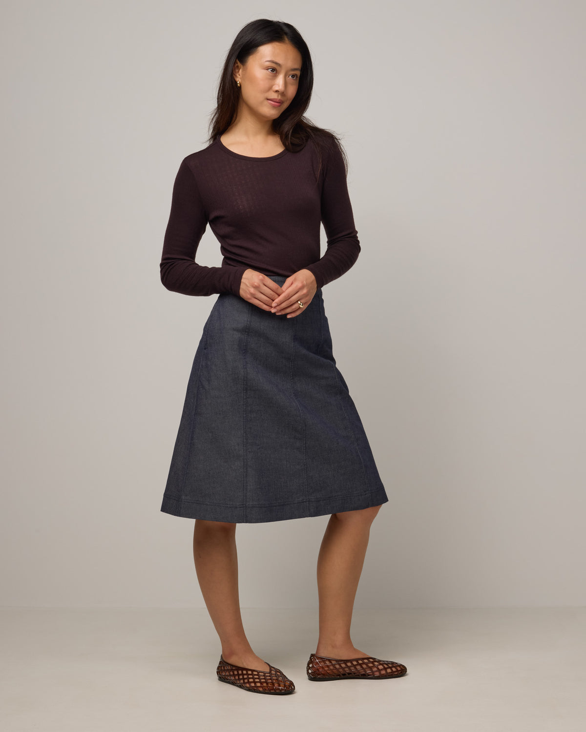 Model wearing Joy Denim Panel Skirt in Indigo Blue. Joy Denim Panel Skirt is a merino wool knee-length skirt available in sizes XS-XXL.