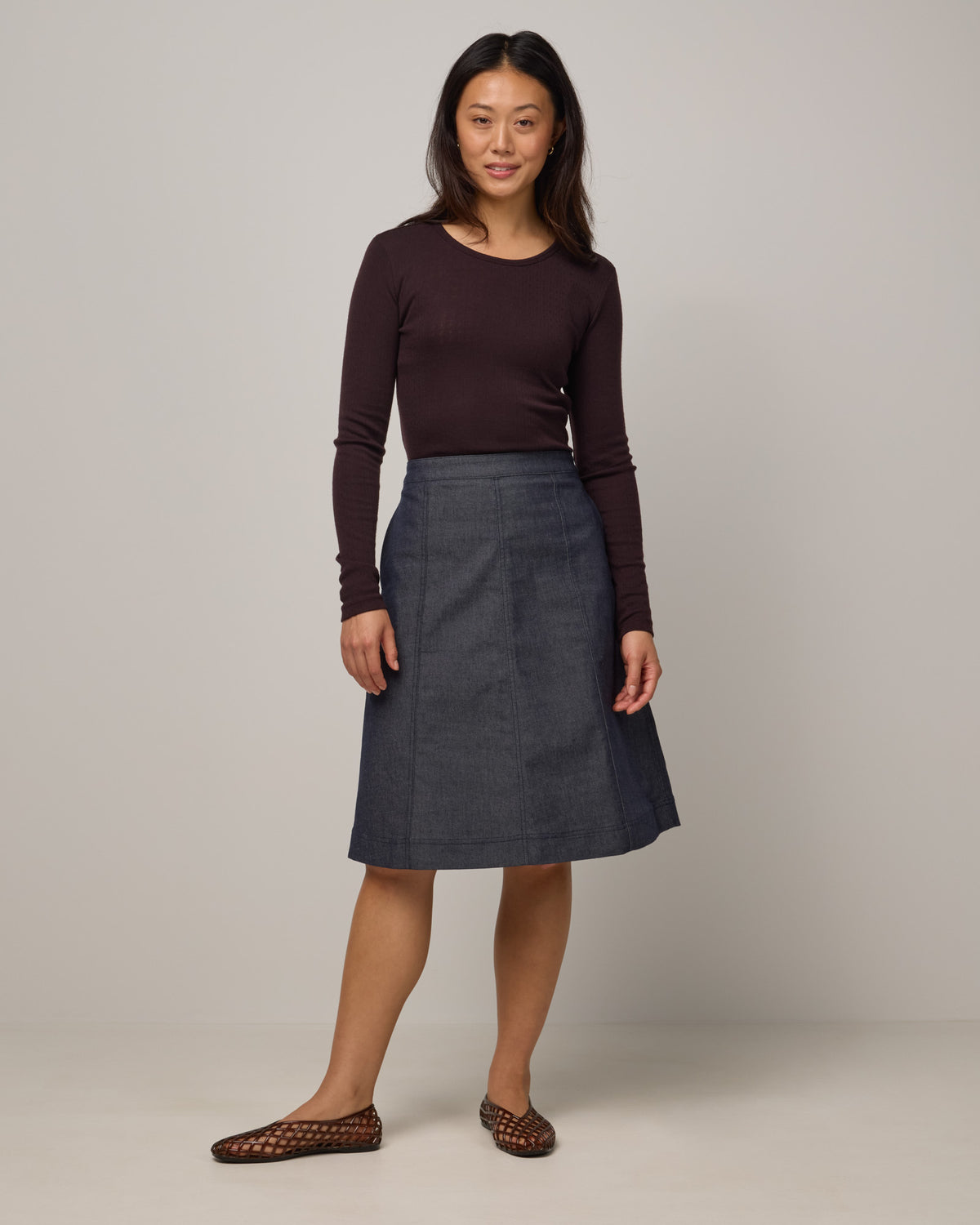 Model wearing Joy Denim Panel Skirt in Indigo Blue. Joy Denim Panel Skirt is a merino wool knee-length skirt available in sizes XS-XXL.