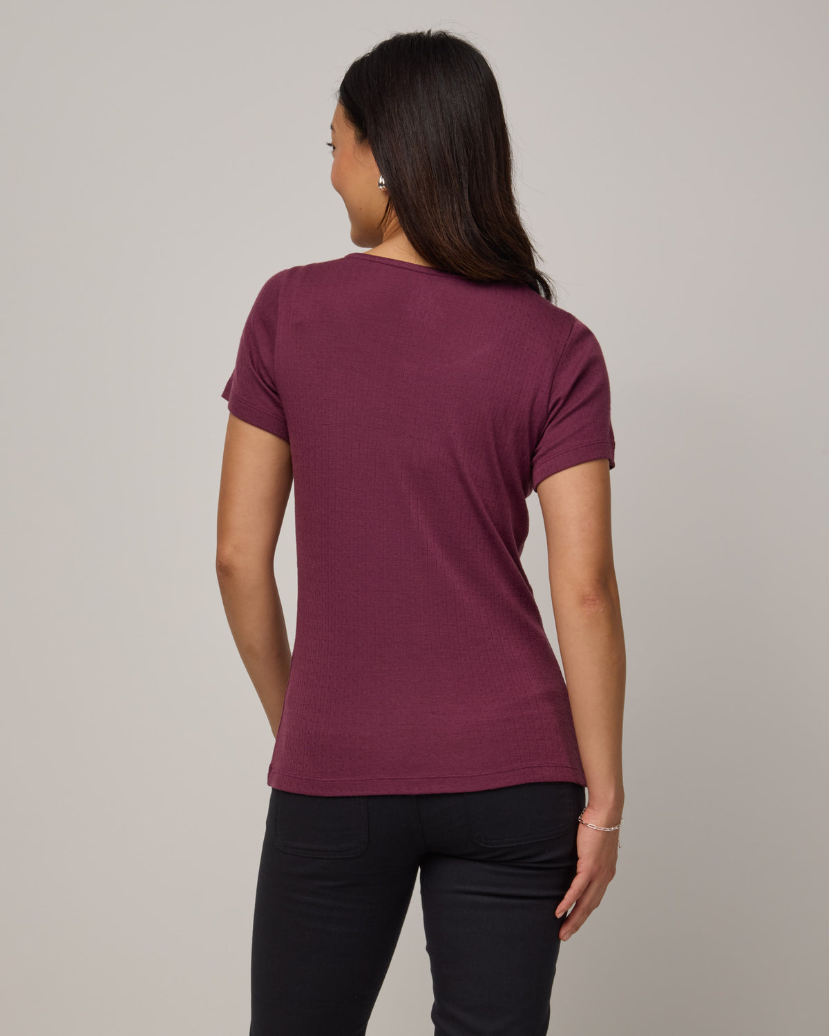 Model wearing Marie Pointelle Henley in Plum, a reddish purple color. Marie Pointelle Henley is a short sleeve, scoop neck, fitted top available in sizes XS-3X. 