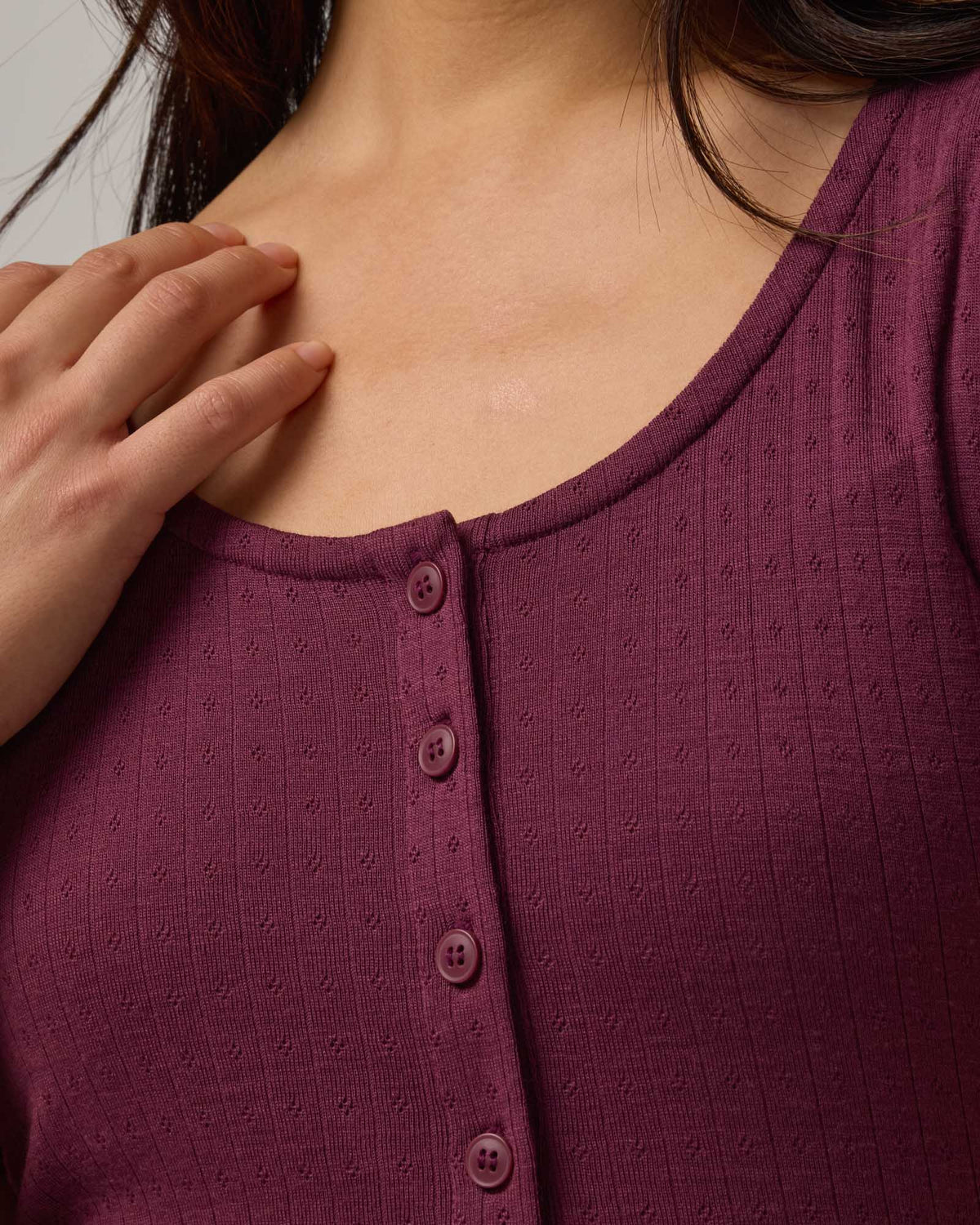 Model wearing Marie Pointelle Henley in Plum, a reddish purple color. Marie Pointelle Henley is a short sleeve, scoop neck, fitted top available in sizes XS-3X. 