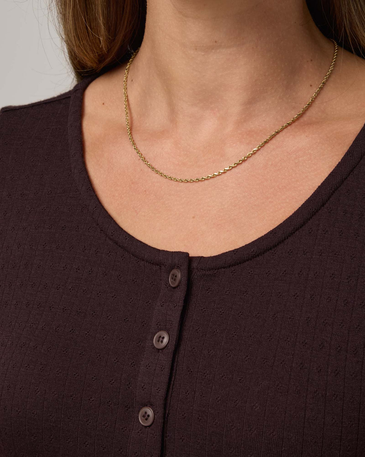 Model wearing Marie Pointelle Henley in Espresso, a dark brown color. Marie Pointelle Henley is a short sleeve, scoop neck, fitted top available in sizes XS-3X. 