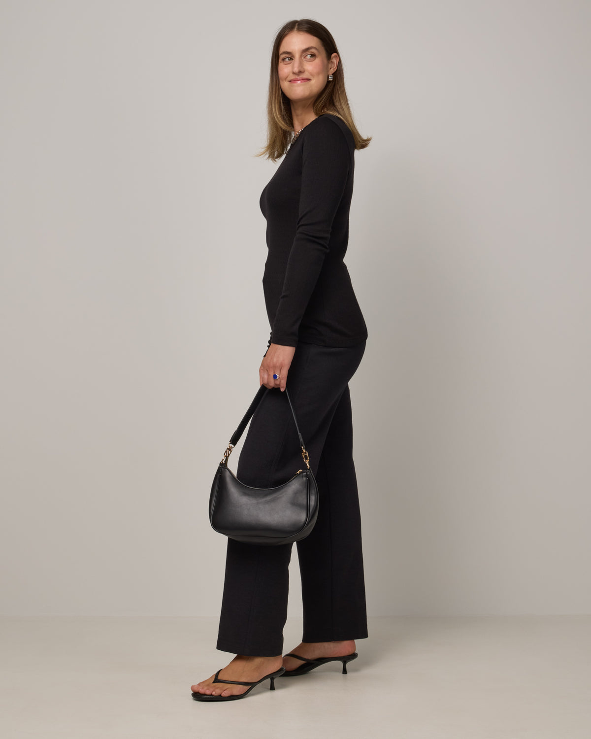 Model wearing Sloan Pointelle Fitted Tee in Black. Sloan Pointelle Fitted Tee is a merino wool long sleeve, crew neck, slim fit tee available in sizes XS-3X.