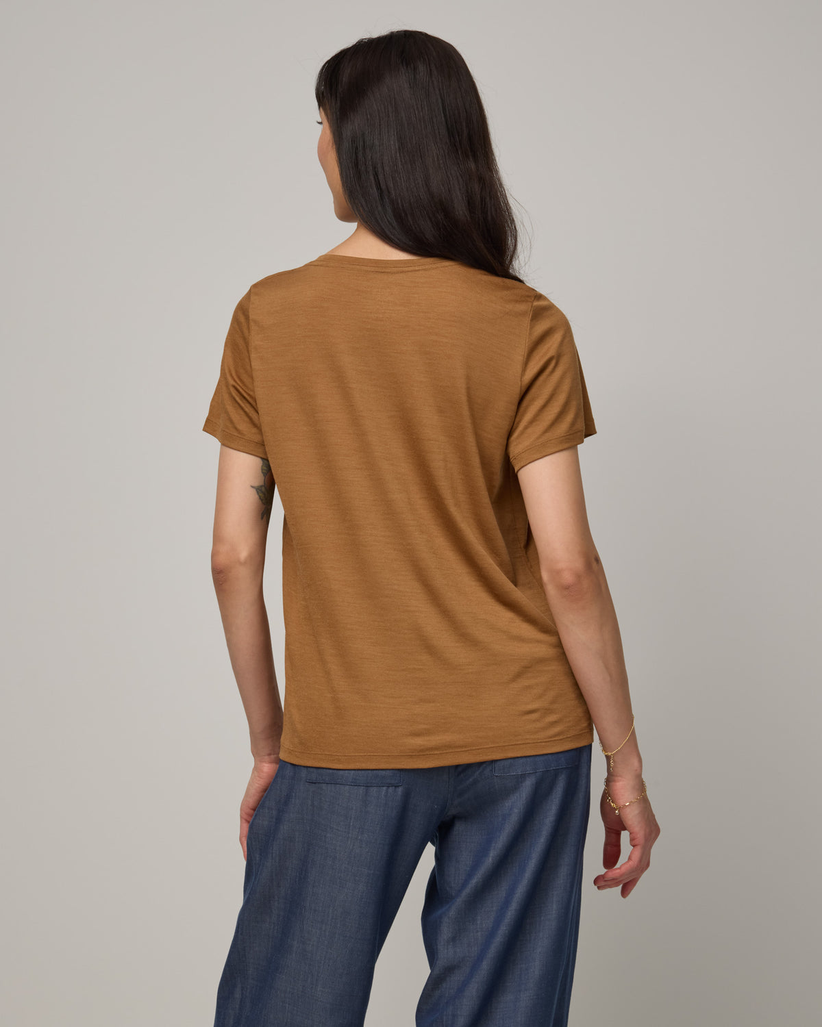 Model wearing Zoe Easy Crew Neck Tee in Camel, a caramel brown color. Zoe Easy Crew Neck Tee is a merino wool short sleeve, crew neck, regular fit tee available in sizes XS-3X.