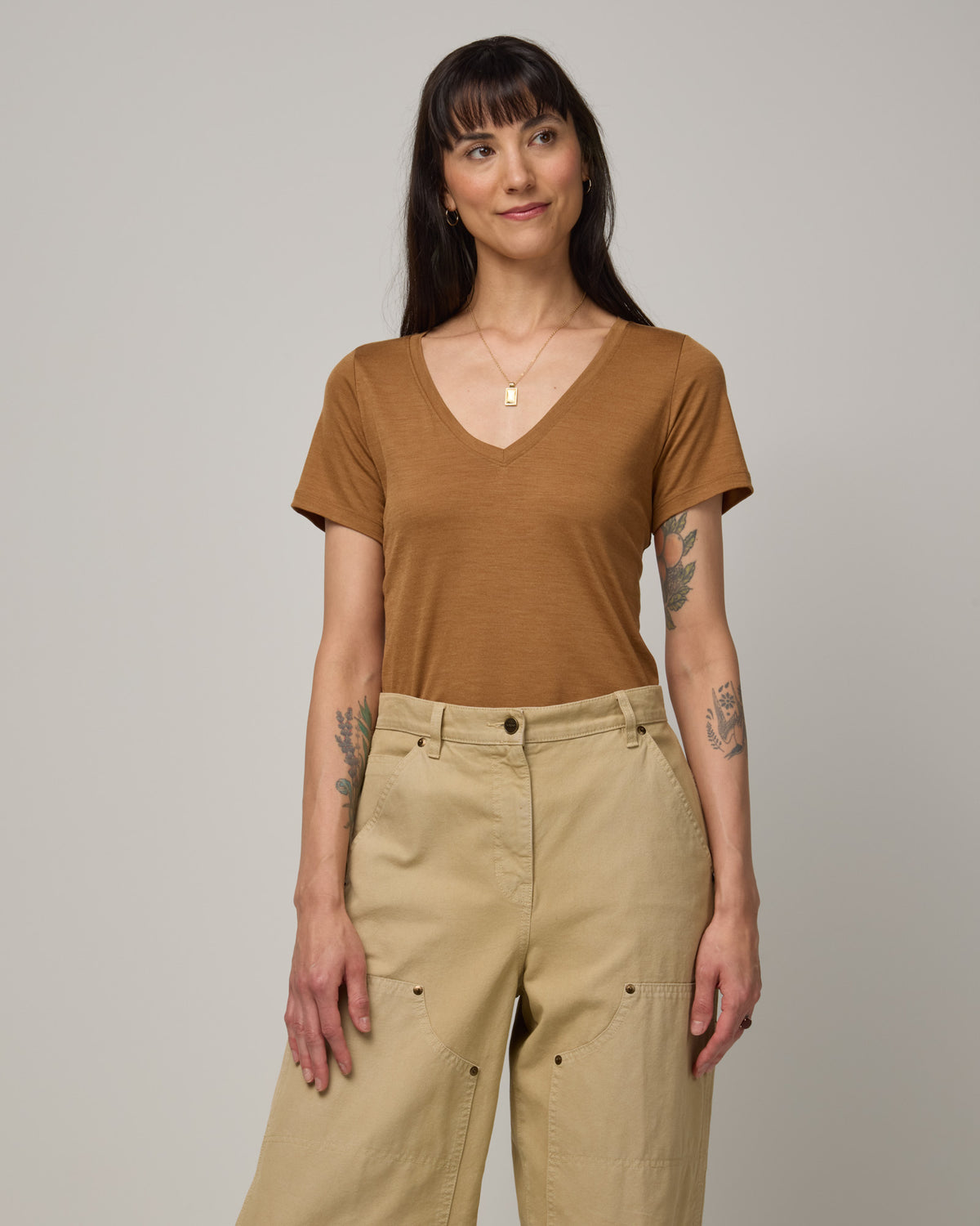 Model wearing Morgan V-Neck Tee in Camel, a caramel brown color. Morgan V-Neck Tee is a merino wool short sleeve, v-neck, regular fit tee available in sizes XS-3X.