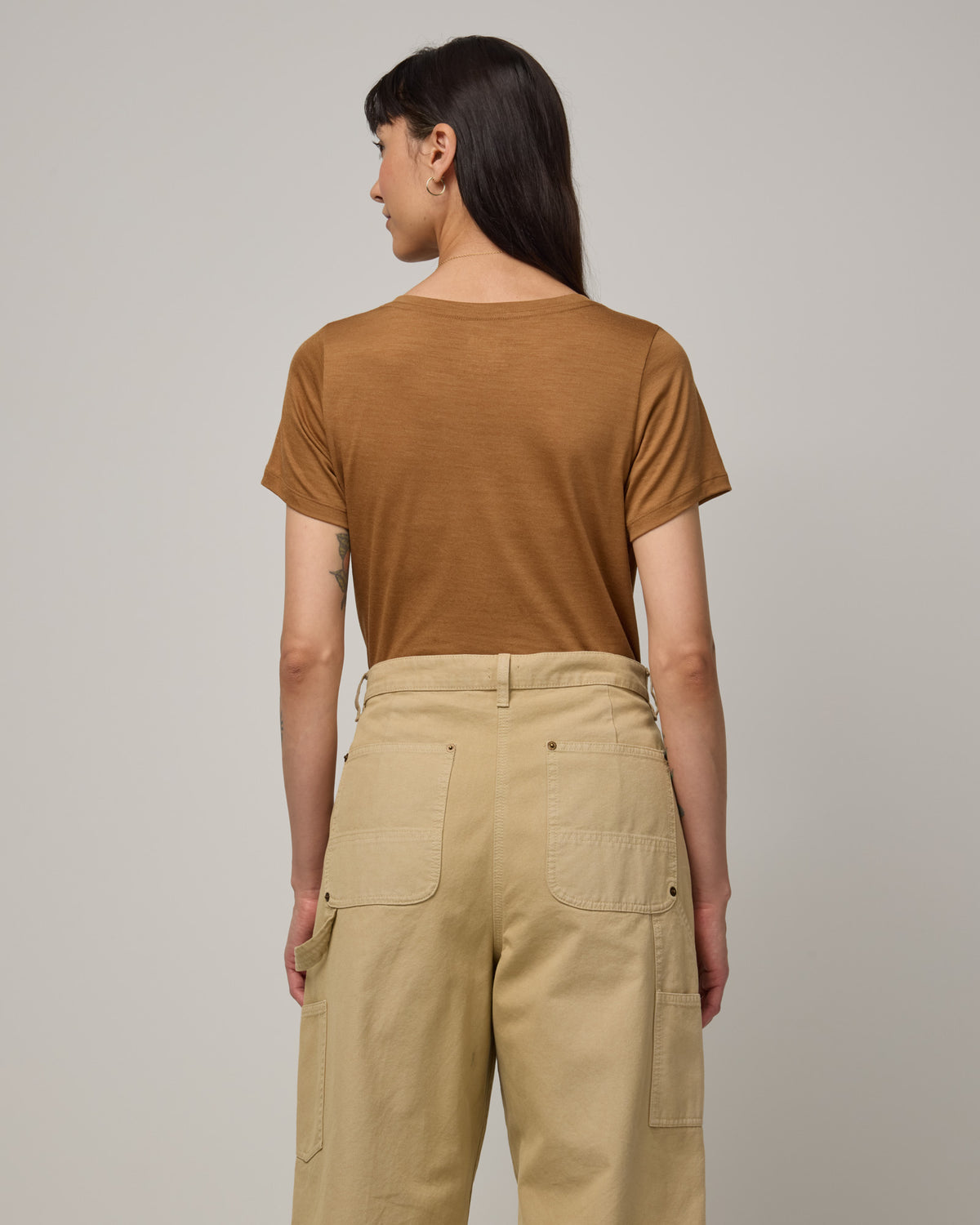 Model wearing Morgan V-Neck Tee in Camel, a caramel brown color. Morgan V-Neck Tee is a merino wool short sleeve, v-neck, regular fit tee available in sizes XS-3X.