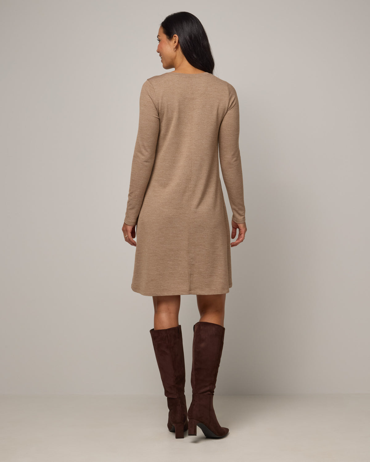 Model wearing Eliza Swing Dress in Camel Heather, a warm heathered tan. Eliza Swing Dress is a merino wool long sleeve, crew neck, knee length swing dress with pockets available in sizes XS-3X Regular, XS-3X Long.