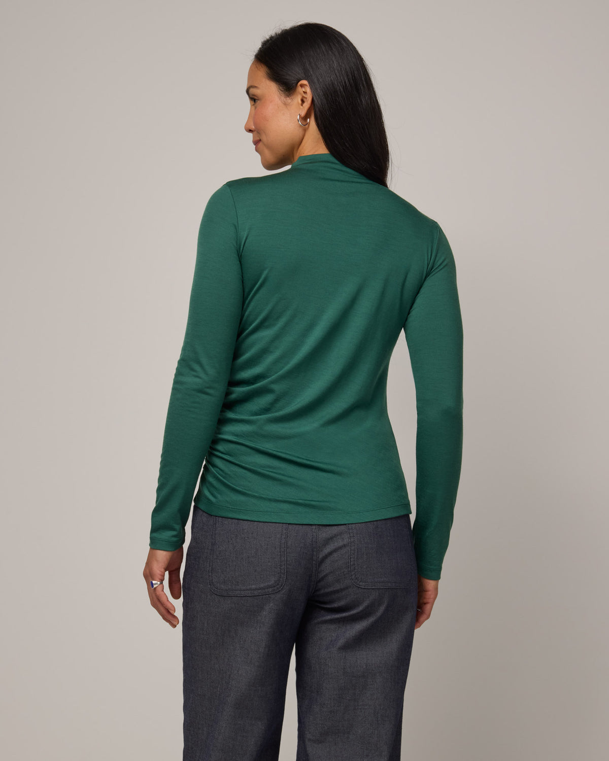 Model wearing Katrina Ruched Top in Emerald green. Katrina Ruched Top is a long sleeve, fitted merino wool mock turtleneck top available in sizes XS-XXL.