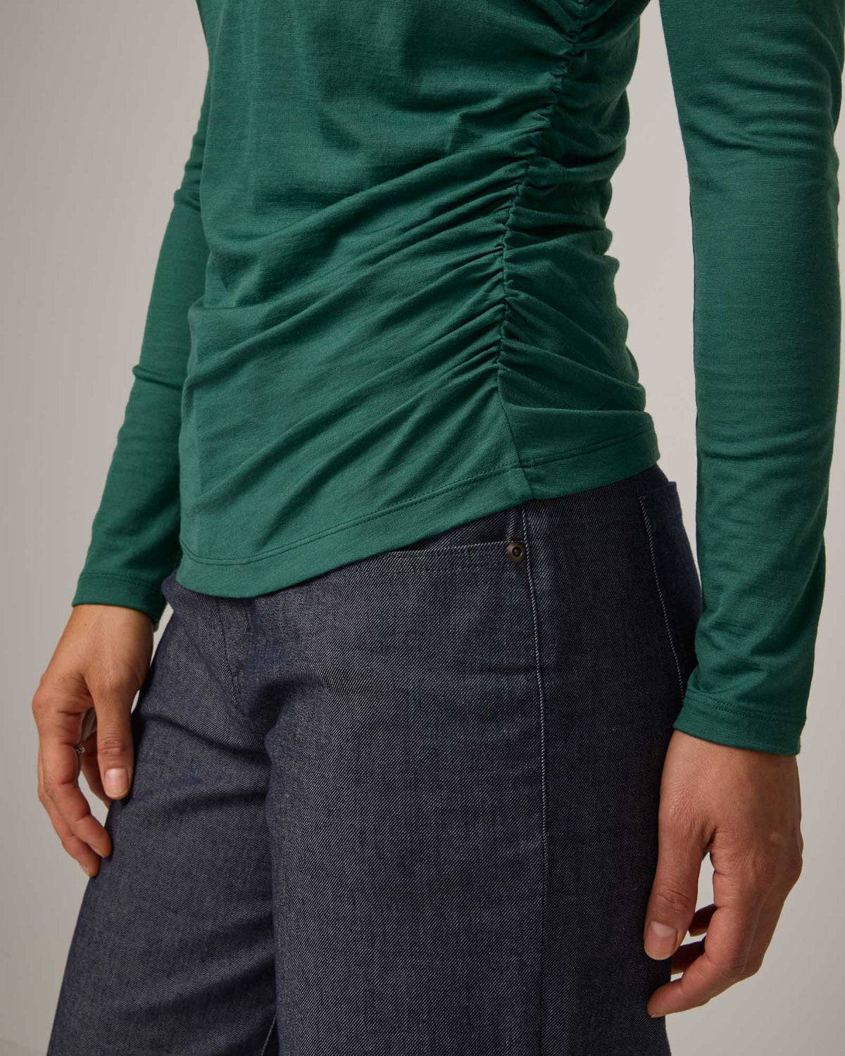 Model wearing Katrina Ruched Top in Emerald green. Katrina Ruched Top is a long sleeve, fitted merino wool mock turtleneck top available in sizes XS-XXL.