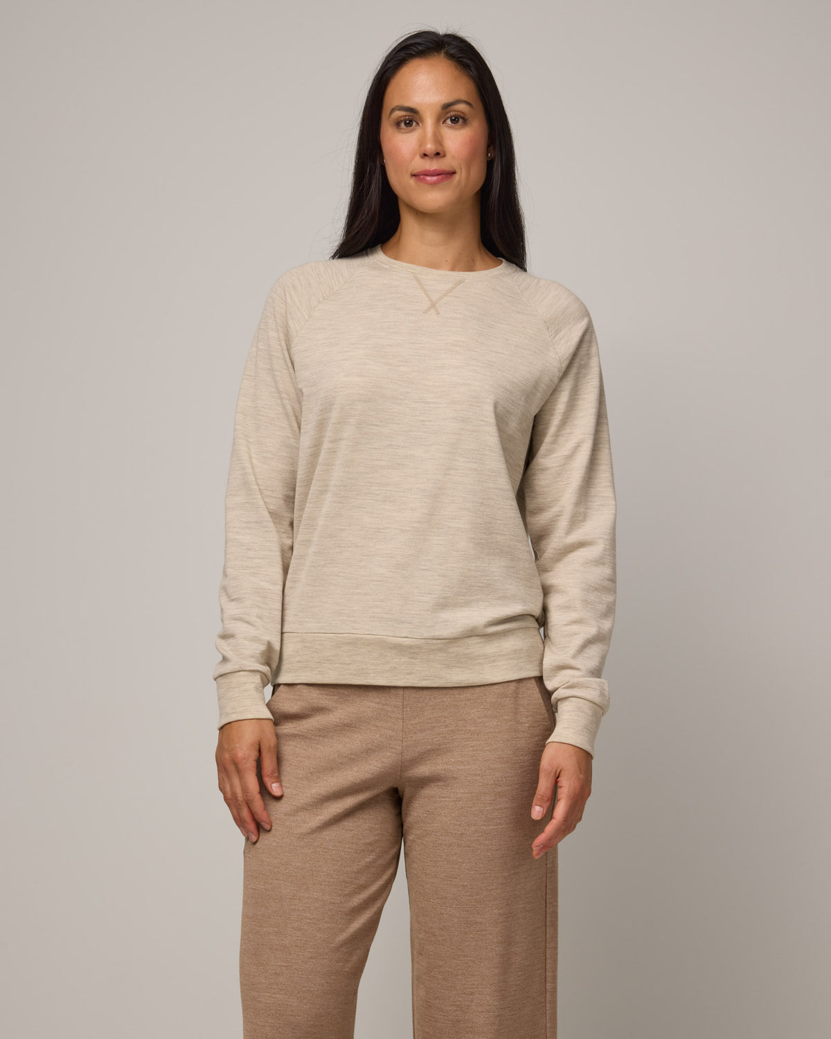 Model wearing Aspen Sweatshirt in Oatmeal Heather, a cream heather color. Aspen Sweatshirt is a merino wool long sleeve, crew neck, regular fit sweatshirt available in sizes XS-3X.