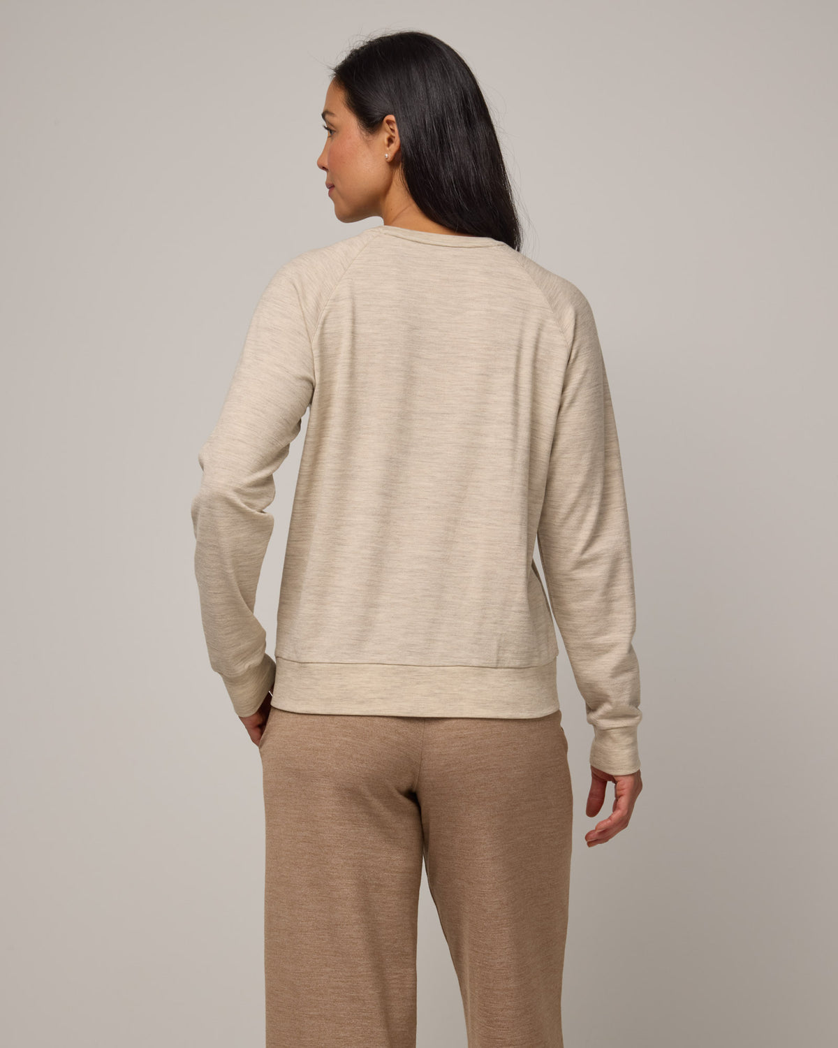 Model wearing Aspen Sweatshirt in Oatmeal Heather, a cream heather color. Aspen Sweatshirt is a merino wool long sleeve, crew neck, regular fit sweatshirt available in sizes XS-3X.
