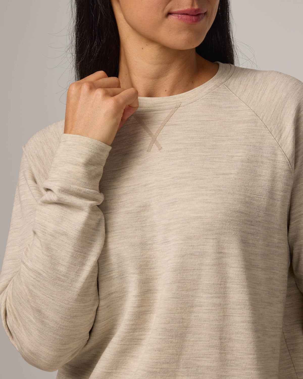 Model wearing Aspen Sweatshirt in Oatmeal Heather, a cream heather color. Aspen Sweatshirt is a merino wool long sleeve, crew neck, regular fit sweatshirt available in sizes XS-3X.