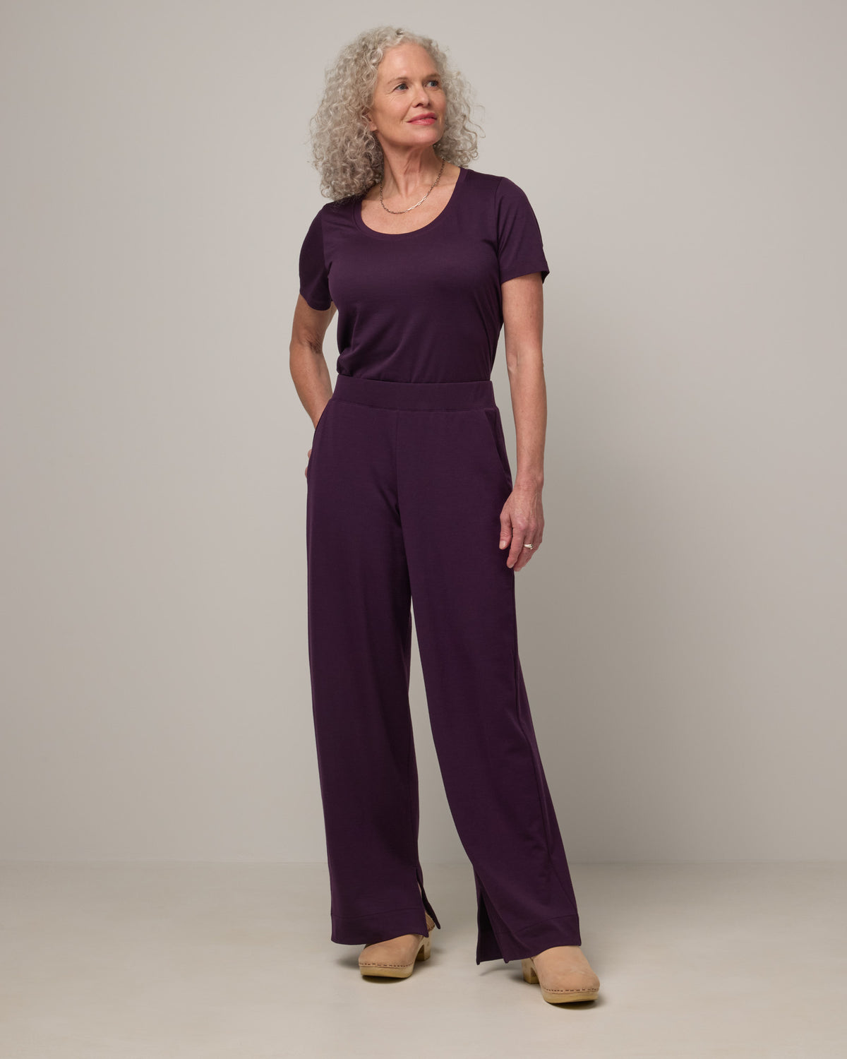 Model wearing Aspen Wide Leg Sweatpantsin Cassis, a deep purple color. Aspen Wide Leg Sweatpant is a merino wool, elastic waist pant available in sizes XS-3X. 