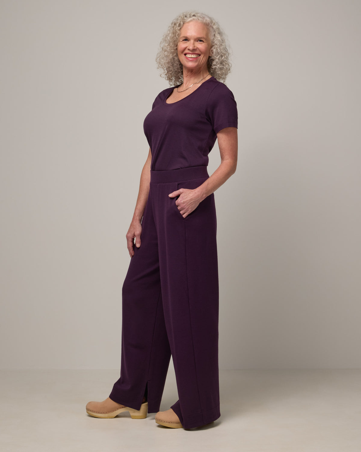 Model wearing Aspen Wide Leg Sweatpantsin Cassis, a deep purple color. Aspen Wide Leg Sweatpant is a merino wool, elastic waist pant available in sizes XS-3X. 