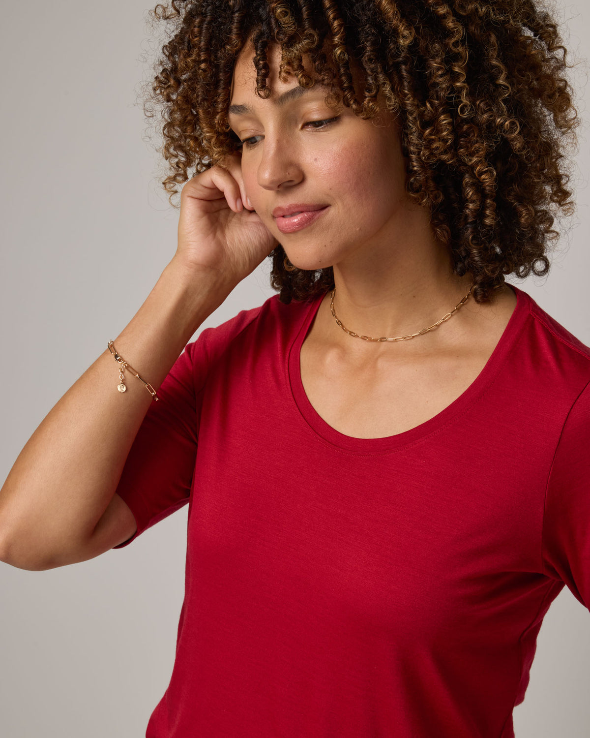 Model wearing Celine Signature Elbow-Sleeve Tee in Cherry Red, a bright red color. Celine Signature Elbow Sleeve Tee is a merino wool scoop neck half-sleeve tee available in sizes XS-3X. 
