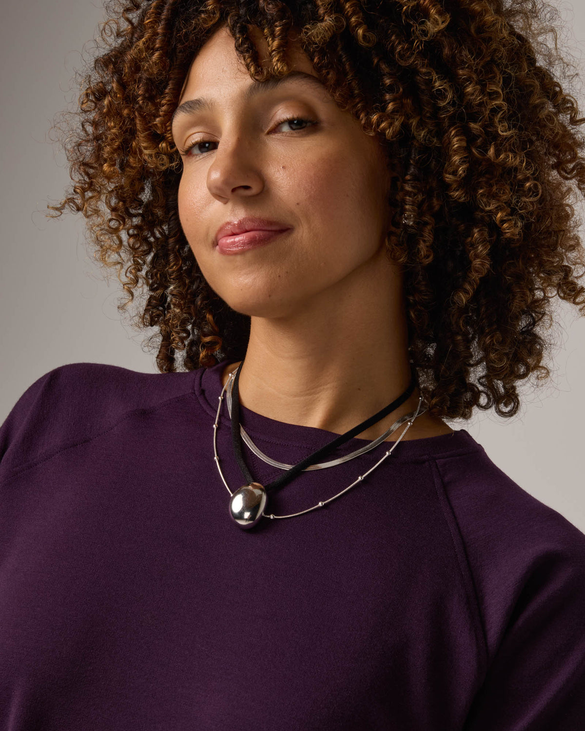 Model wearing Aspen Sweatshirt in Cassis, a dark purple color. Aspen Sweatshirt is a merino wool long sleeve, crew neck, regular fit sweatshirt available in sizes XS-3X.